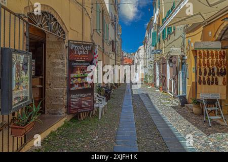 ALGHERO, ITALIE - 4 JUILLET 2024 : rue pittoresque médiévale, typique sarde, avec de petites boutiques de souvenirs traditionnelles. Banque D'Images