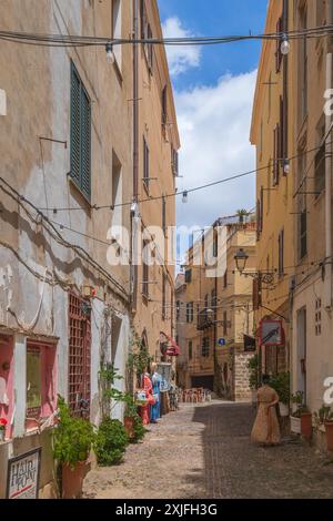 ALGHERO, ITALIE - 3 JUILLET 2024 : rue pittoresque médiévale typique sarde avec petits restaurants traditionnels et boutique de souvenirs. Banque D'Images