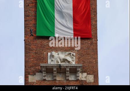 Vicence, VI, Italie - 10 mai 2024 : détail de l'ancienne Tour et lion ailé et grand drapeau italien Banque D'Images