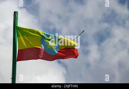 Le drapeau éthiopien, avec ses bandes vertes, jaunes et rouges et son emblème central, agite fièrement au vent contre un ciel nuageux Banque D'Images