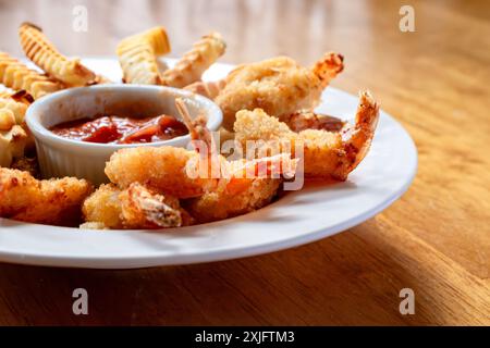 Crevettes frites et frites cuites dans une friteuse à air. Disposé dans un bol blanc peu profond avec sauce cocktail au centre. Banque D'Images