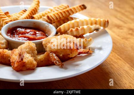 Crevettes frites et frites cuites dans une friteuse à air. Disposé dans un bol blanc peu profond avec sauce cocktail au centre. Banque D'Images