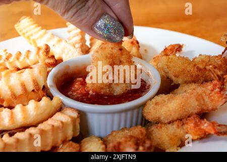 Crevettes frites et frites cuites dans une friteuse à air. Disposé dans un bol blanc peu profond avec sauce cocktail au centre. Banque D'Images