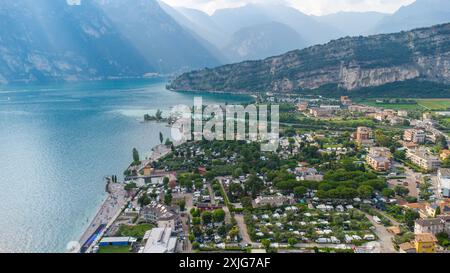 Torbole, Lac de Garde, Italie - 18 juillet 2024 : vue aérienne de Torbole sur le Lac de Garde en Italie. Au premier plan, vous pouvez voir le village avec ses maisons et ses rues. Le lac s'étend majestueusement au loin, entouré de hautes montagnes *** Luftaufnahme von Torbole am Gardasee en Italien. IM Vordergrund sieht man das Dorf mit seinen Wohnhäusern und Straßen. Der See erstreckt sich majestätisch in die Ferne, umgeben von hohen Bergen Banque D'Images