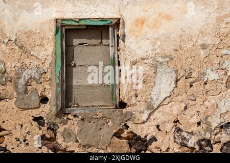 Décollé de la façade d'une maison abandonnée. Le cadre de fenêtre, qui était vert, est maintenant sans verre et muré. Journée ensoleillée. Caleta del Sebo, la Grac Banque D'Images