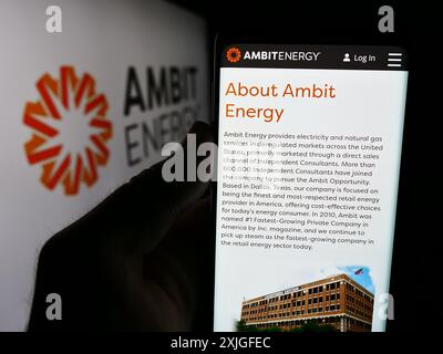 Personne tenant un smartphone avec la page Web de la société américaine de marketing multi-niveaux Ambit Energy devant le logo. Concentrez-vous sur le centre de l'écran du téléphone. Banque D'Images