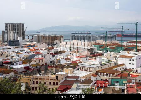 Une vue aérienne panoramique du paysage urbain de Gibraltar, avec des bâtiments colorés, des grues et le port avec des navires amarrés. Banque D'Images