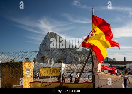 Un manifestant arborant un drapeau espagnol se tient près de la frontière de Gibraltar, au Royaume-Uni, avec la célèbre formation rocheuse en arrière-plan. Banque D'Images