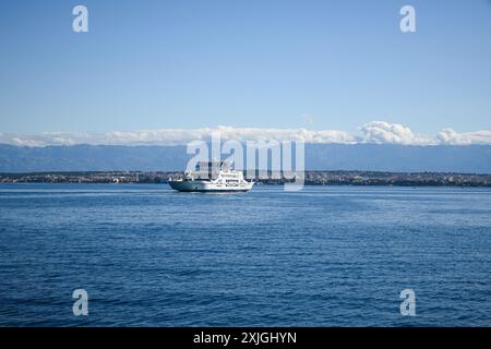 Un ferry naviguant à travers la mer Adriatique vers une île croate avec des montagnes en arrière-plan par une journée d'été ensoleillée. Banque D'Images