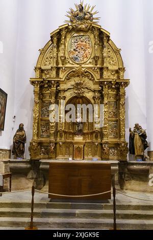 Astorga, Espagne - 4 juin 2023 : un grand autel d'or finement sculpté se dresse dans une pièce faiblement éclairée, avec des statues et des sculptures représentant des figu religieux Banque D'Images