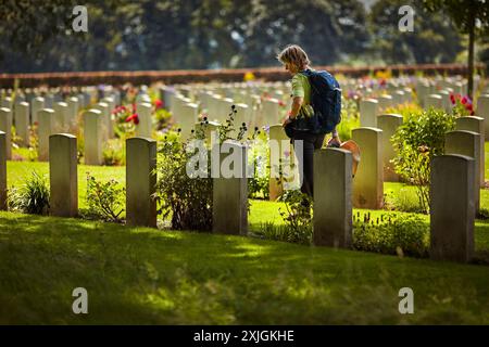 Groesbeek, pays-Bas. 18 juillet 2024. Un participant aux Marches des 4days passe devant les tombes de soldats tombés au combat lors de la deuxième Guerre mondiale le troisième jour de marche au cimetière de guerre canadien de Groesbeek. Le cimetière contient les tombes de 2 619 soldats morts pendant la seconde Guerre mondiale. Les marcheurs se tiennent devant la Croix du sacrifice, une croix faite de pierre de Portland avec une épée en métal sur le dessus. Cette année marque le 80e anniversaire d'un raid aérien de grande envergure à Groesbeek dans le cadre de l'opération Market Garden. Crédit : SOPA images Limited/Alamy Live News Banque D'Images