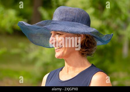 Une femme âgée dans un chapeau bleu souriant sur fond de nature. Banque D'Images