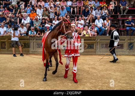 Un membre de la Giraffa Contrada vêtu d'un costume médiéval participe à Une procession historique, Piazza Del Campo, le Palio, Sienne, Italie. Banque D'Images