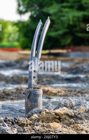 Image verticale d'un tube de cuvelage avec des tuyaux de boucle de terre en polyéthylène en cours d'installation dans un nouveau champ de puits géothermique. Banque D'Images