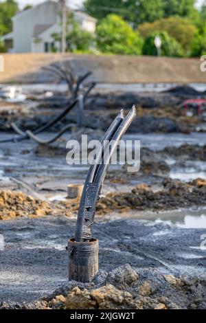 Image verticale d'un tube de cuvelage avec des tuyaux de boucle de terre en polyéthylène en cours d'installation dans un nouveau champ de puits géothermique. Banque D'Images