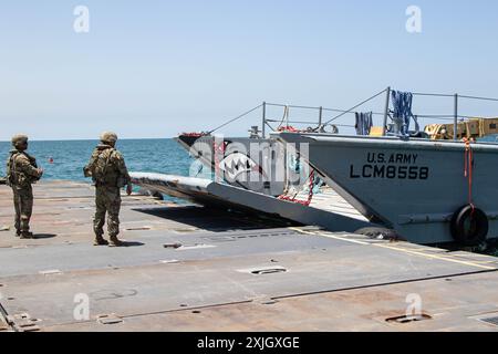 Les soldats de l'armée américaine affectés à la 7e brigade de transport (expéditionnaire) et les marins de l'US Navy affectés au bataillon de construction amphibie 1, transportent la jetée du Trident à travers la mer Méditerranée, le 19 juin 2024, près de la côte de Gaza. Après une suspension temporaire en raison de la présence d'états de mer lourds, le quai temporaire, qui fait partie de la capacité conjointe logistique Over-the-Shore, a été réancré pour reprendre l'acheminement maritime de l'aide humanitaire internationale aux citoyens de Gaza. (Photo de l'armée américaine par le sergent d'état-major Malcolm Cohens-Ashley) Banque D'Images