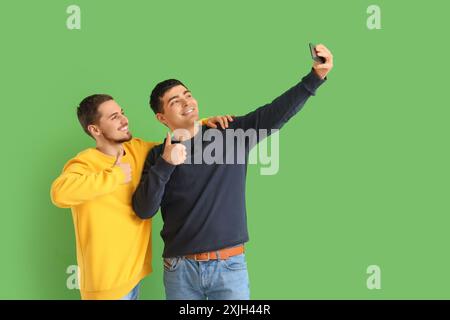 Beaux jeunes frères prenant selfie sur fond vert Banque D'Images