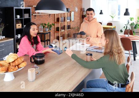 Femme barista asiatique prenant le paiement du visiteur dans le café Banque D'Images