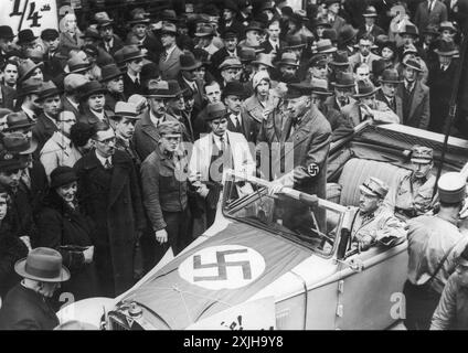 Berlin, Allemagne. Le 1er avril 1933, au cours d'une campagne de boycott antisémite et de propagande harcelant les entreprises juives, un homme avec des symboles nazis sur sa voiture et son brassard rallie la foule pour participer. Banque D'Images