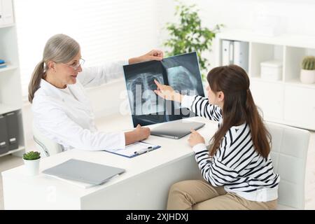 Les maladies pulmonaires. Médecin montrant une radiographie thoracique à son patient à table en clinique Banque D'Images