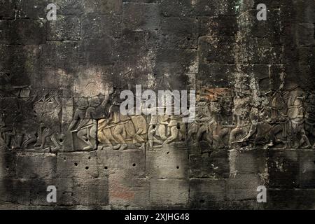 Bas-reliefs altérés, représentant une scène de guerre, sur le mur du temple Bayon à Angkor Thom, Siem Reap, Cambodge. Banque D'Images