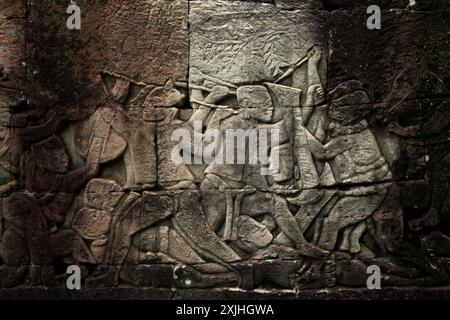 Bas-reliefs altérés, représentant une scène de guerre, sur le mur du temple Bayon à Angkor Thom, Siem Reap, Cambodge. Banque D'Images