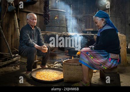 Fleur Hmong homme et femme décortiquant du maïs dans leur cuisine à bac Ha, province de Lao Cai, Vietnam Banque D'Images