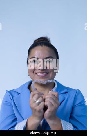 Heureuse femme mexicaine souriante tenant un aligneur dentaire clair en forme de coeur Banque D'Images