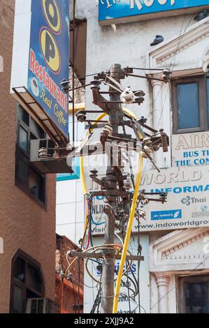 Câbles et poteaux électriques vieux, rouillés et inutilisés sur une rue de New Delhi, en Inde, mettant en évidence le vieillissement des infrastructures Banque D'Images