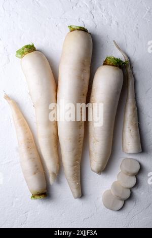 Racines de radis daikon blanc sur fond blanc gros plan. Vue de dessus. Photographie culinaire Banque D'Images