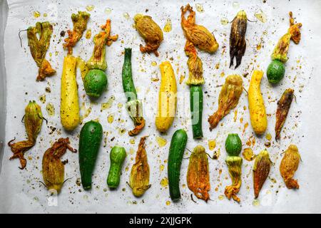 Cuite de courgettes différentes avec des fleurs après la cuisson dans le four. Vue de dessus. Courgettes rôties aux épices de près. Courgettes cuites au four avec huile d'olive, sel et poivre Banque D'Images