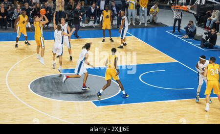 Reportage de style TV du championnat de basket-ball : équipe jaune passant le ballon entre coéquipiers, attaquant visant à marquer un but de deux points à distance. Concept Sport Channel. Banque D'Images