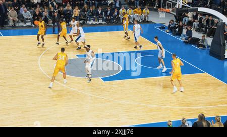Vidéo de style diffusion TV du Championnat de basket-ball : équipe jaune passant le ballon entre coéquipiers, attaquant visant à marquer un but de deux points à distance. Concept Sport Channel. Banque D'Images