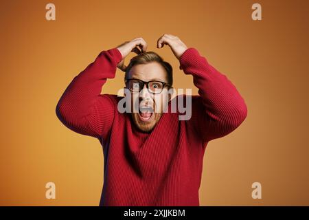 Homme élégant en pull rouge, tenant la tête en détresse. Banque D'Images