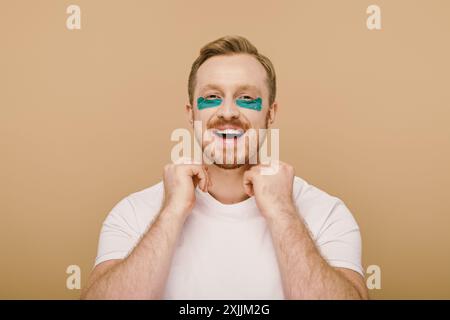 Homme barbu avec des patchs pour les yeux bleus concentré sur sa routine de soins de la peau. Banque D'Images