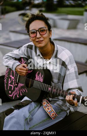 Une jeune femme joue de la guitare dans la rue. Banque D'Images