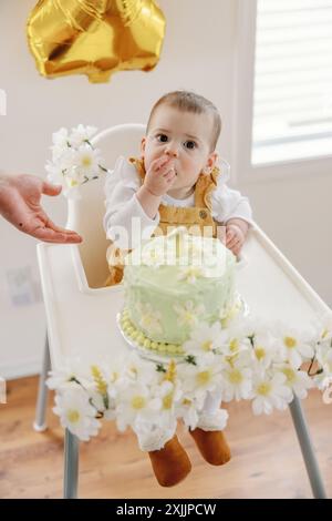 Premier anniversaire de bébé avec gâteau, ballon d'or et décorations florales Banque D'Images