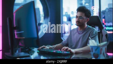 Développeur de logiciels portant Sci-Fi Monocle avec fonctions de réalité augmentée et d'intelligence artificielle. Jeune homme beau travaillant sur un ordinateur dans une salle d'agence de cyberréalité futuriste Banque D'Images