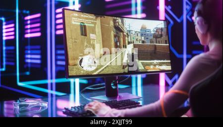 Professionnel eSports Gamer jouant 3D First Person Shooter jeu vidéo avec Fast Fun action sur ordinateur de bureau. Femme participant à un tournoi Cyber Gaming dans l'élégante salle moderne Neon Banque D'Images
