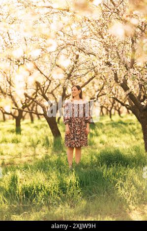 Une jeune femme profite de la beauté d'un bosquet en fleurs au printemps, entourée de verdure et d'arbres en fleurs Banque D'Images