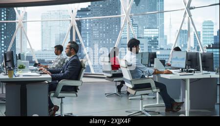 Équipe de jeunes professionnels indiens talentueux travaillant dans Corporate Hedge Fund. Analystes financiers et gestionnaires travaillant sur des ordinateurs dans un bureau d'affaires sud-asiatique avec Scenic City View Banque D'Images