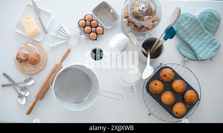 Farine, oeufs et beurre sur table pour la cuisson, gâteau et dessert dans la maison avec vue de dessus, lait et sucre. Poudre, fouet et muffin sur le comptoir de cuisine Banque D'Images