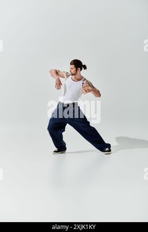 Un homme caucasien en tenue tendance danse gracieusement dans une chemise blanche. Banque D'Images