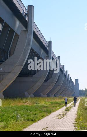 19 juillet 2024, Saxe-Anhalt, Wolmirstedt : les marcheurs marchent le long du pont du canal de Magdebourg. Le pont du canal de Magdebourg se compose du pont avant-pays de 690 mètres de long et du pont fluvial de 228 mètres de long. Au total, le pont canal mesure 918 mètres de long, ce qui en fait le plus long pont canal au monde. Il transporte le trafic maritime du canal Mittelland à travers l'Elbe. La forme des piliers du pont de l'estran est destinée à ressembler aux côtes d'un navire. La structure fait partie de l'intersection de la voie navigable de Magdebourg. Environ 68 000 mètres cubes de béton armé étaient Banque D'Images