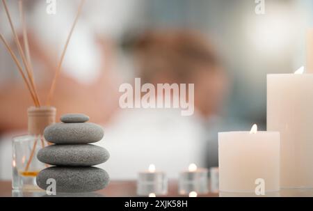 Spa, bougies et pile de pierres chaudes pour le luxe, le bien-être et le traitement de santé avec atmosphère zen. Calme, beauté et bouquet de roches chaudes dans les soins de la peau Banque D'Images