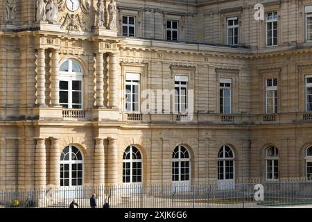 Paris, France - 18 octobre 2023 : Un grand bâtiment en pierre avec des détails ornés et des fenêtres cintrées se dresse derrière une clôture en fer forgé à Paris, France. Banque D'Images