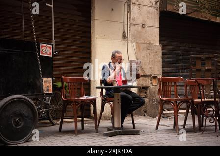 Le Caire, Égypte. 14 juin 2024. Un égyptien fume, boit du thé et lit un journal dans un café local du centre-ville du Caire. Crédit : SOPA images Limited/Alamy Live News Banque D'Images