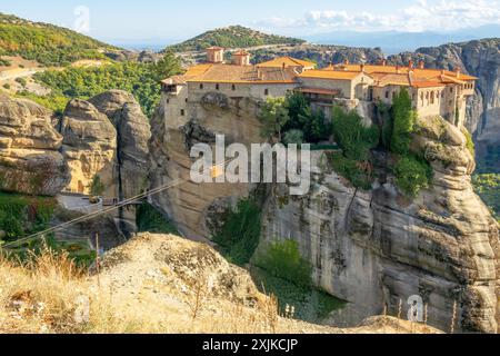 Grèce. Journée d'été ensoleillée dans la vallée de Kalambaka. Monastère aux toits rouges sur la falaise et le funiculaire Banque D'Images