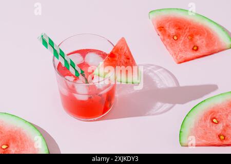 Scène d'été avec boisson tropicale rafraîchissante de pastèque et tranches de pastèque fraîche sur fond rose. Soleil et ombres. Concept de cocktail minimal. Banque D'Images