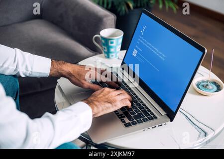 Homme avec ordinateur portable montrant l'écran bleu de la mort ou BSOD sur l'écran du moniteur. Système d'exploitation Microsoft Windows 10 défectueux. Rosario, Argentine - 19 juillet Banque D'Images